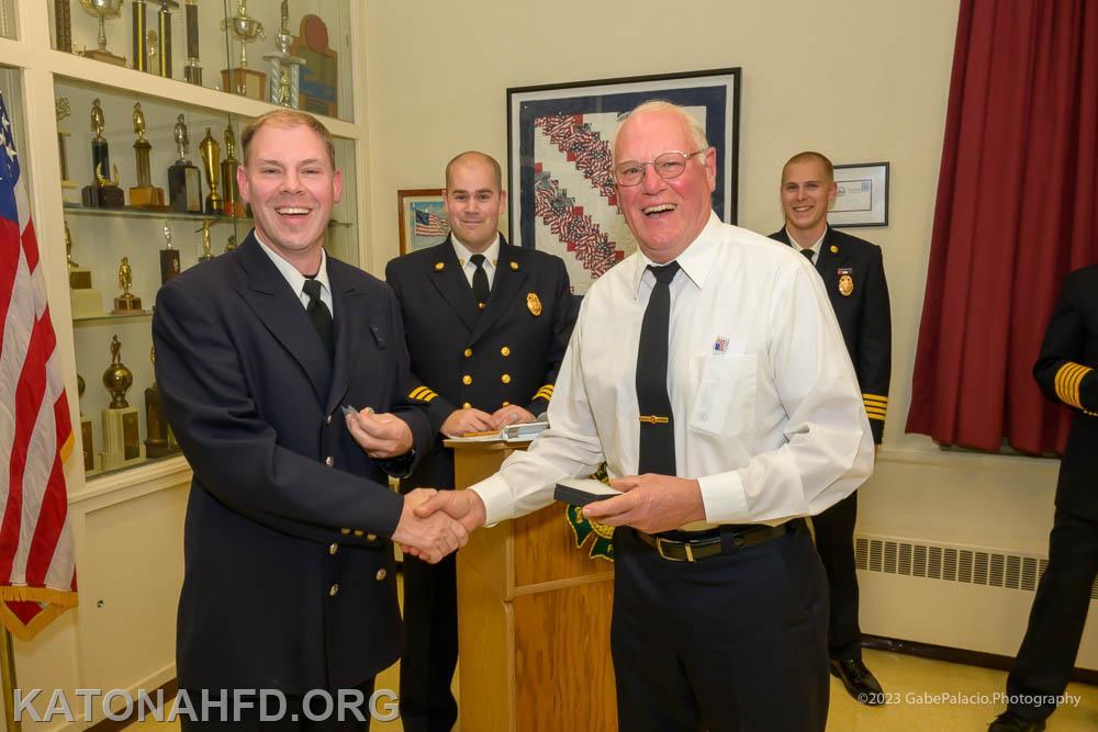Firefighter Hank Tschorn (right) presented a 25-year badge to his son, Dan Tschorn. Photo by Gabe Palacio. Photo by Gabe Palacio.